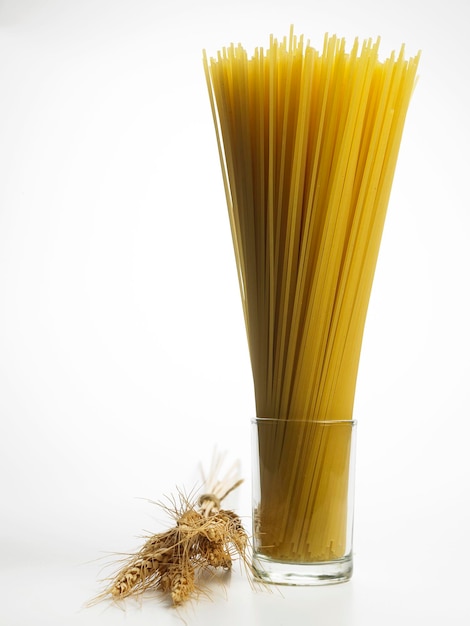 Photo close-up of pasta in jar by ear of wheat against white background