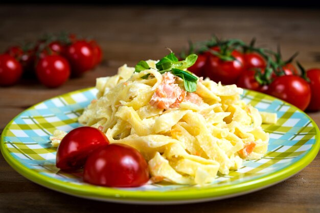 Photo close-up of pasta and tomato slices in plate on table