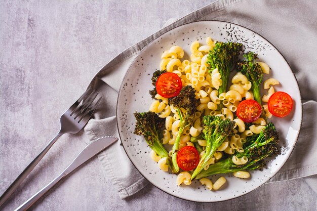 Close up of pasta with cherry tomatoes and fried broccoli sprouts on a plate top view