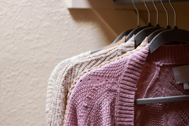 close up of pastel warm knitted cardigan sweater hanging in the closet. Cozy fall and winter wardrob