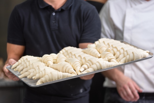 Close up of Pastry Chef showing a tray of fresh raw croissants dough.