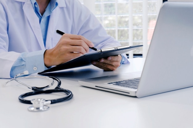 close up of patient and doctor taking notes or Professional medical doctor in white uniform gown coat interviewใ