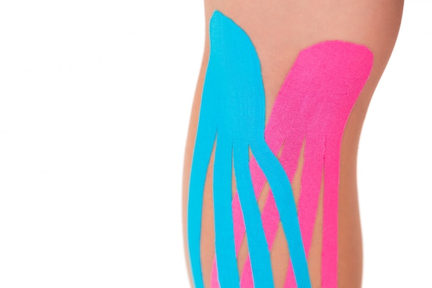 Close up of patients knee with applied pink and blue kinesio tape