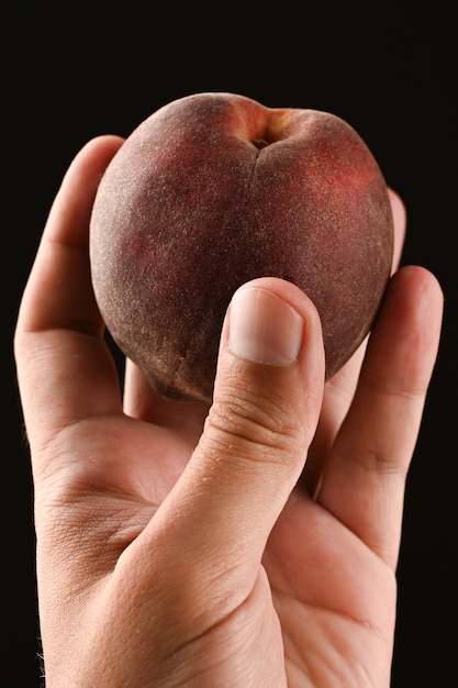 Close up of peach in hand isolated