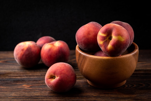 Close up peaches in wooden bowl on table