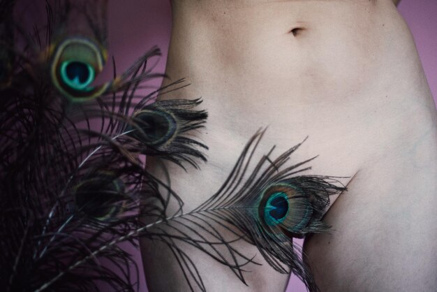 Foto close-up di piume di pavone che coprono una donna nuda