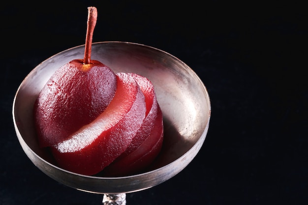 Close-up of a pear in red wine isolated on black