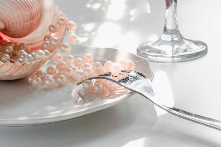 Photo close-up of pearls with seashell and fork in plate on table
