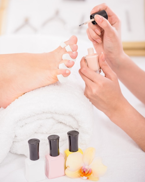 Close-up of pedicurist applying nail polish to the toenails.