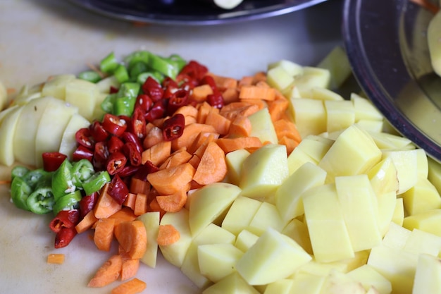 Photo close up of peeled and chopped potatoes carrots and peppers prepared for cooking