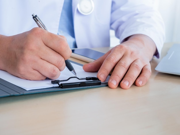 의사가 책상 위에 있는 펜을 닫고 의사가 클립보드에 환자 파일 문서로 글을 쓰는 동안 복사 공간이 있는 진료소 사무실 구강 치과 검사 및 환자 약속 개념