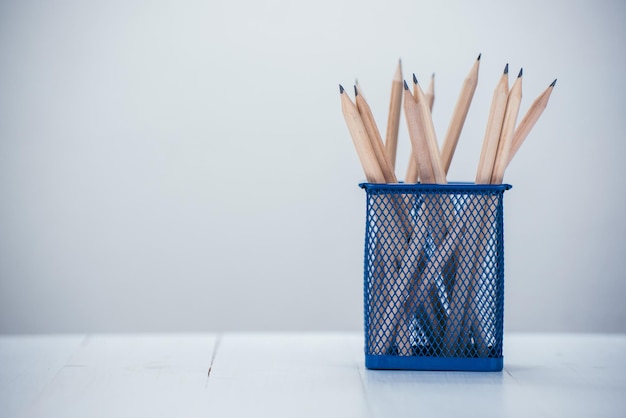 Photo close-up of pencils in desk organizer on table against white background