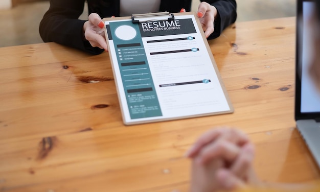 Photo close up people hands on a wooden table boss and woman during interview director hr manager holding resume paper woman talking about yourself hr recruitment and hiring concept