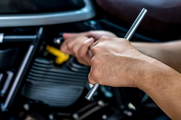 閉じる。手を持っている人はオートバイを修理していますレンチとドライバーを使用して