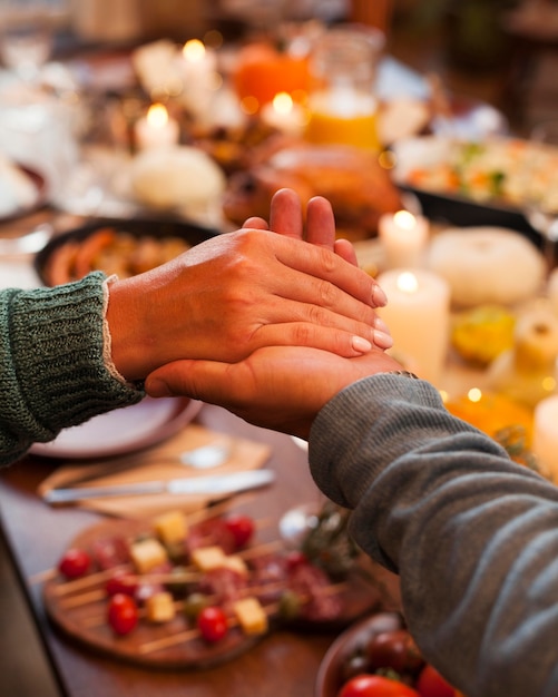 写真 夕食時に手を繋いでいるクローズアップの人々