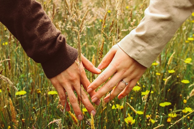 Photo close-up of people holding hands on grass field