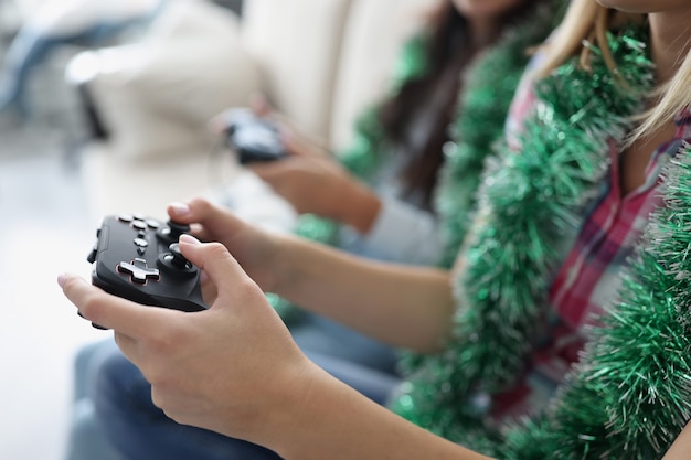 Photo close-up of people pressing buttons on joystick, playing video games for fun, killing time on weekend, wearing festive decor. funny pastime, hobby, addiction, leisure, new year concept