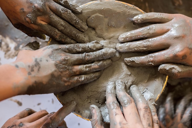 Photo close-up of people touching mud in container