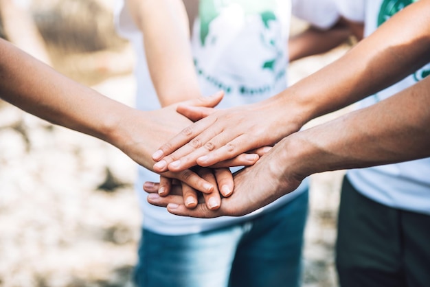 Primo piano di persone che fanno volontariato per il lavoro di squadra mettendo insieme le manistack di maniunità e lavoro di squadra nella giornata mondiale dell'ambiente