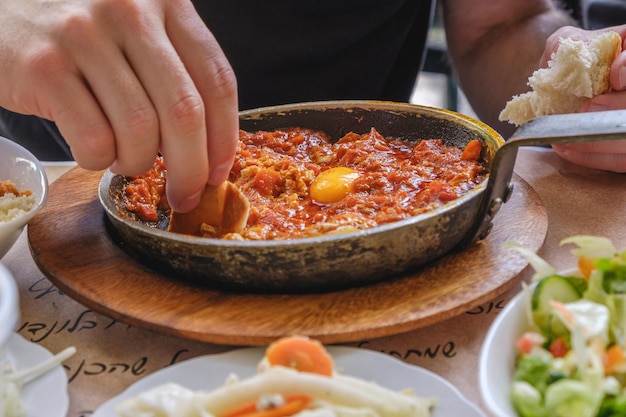 Photo close-up of person eating shakshouka on table