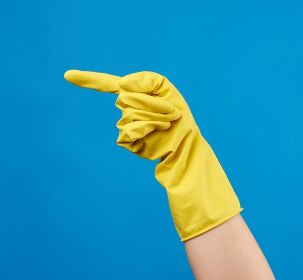 Close-up of person hand holding yellow umbrella against blue sky