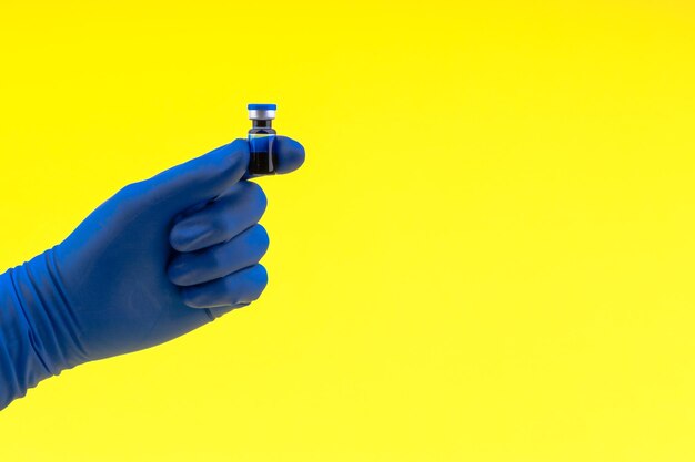 Close-up of person holding ampoule against yellow background