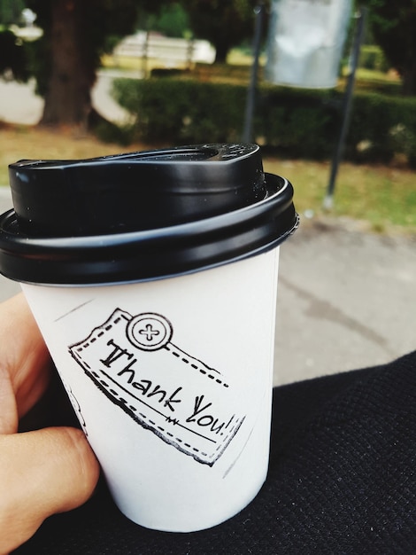 Foto close-up di una persona che tiene una tazza di caffè