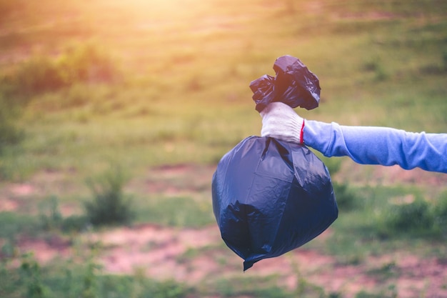 Photo close-up of person holding garbage bag on plants