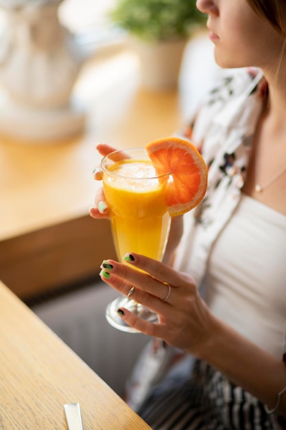 close up of a person holding a glass of orange juice