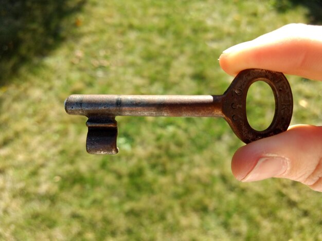 Photo close-up of person holding key over grass