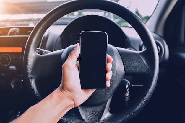 車の中で携帯電話を握っている人のクローズアップ