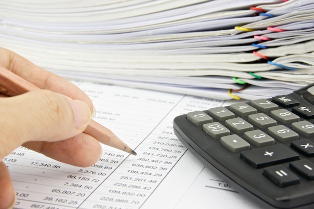 Close-up of person holding pencil over paper with data