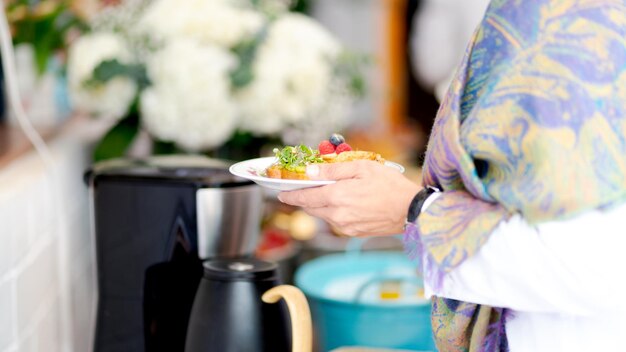 close-up of a person holding a plate next to a coffee pot. healthy and organic breakfast.