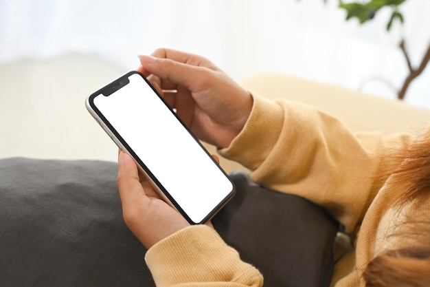 アプリディスプレイのためにホワイトスクリーンでスマートフォンを握っている近距離の人