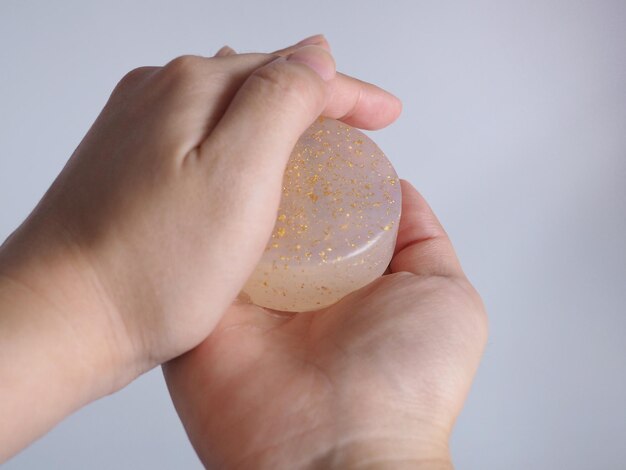 Foto close-up di una persona che tiene il sapone in mano su uno sfondo bianco