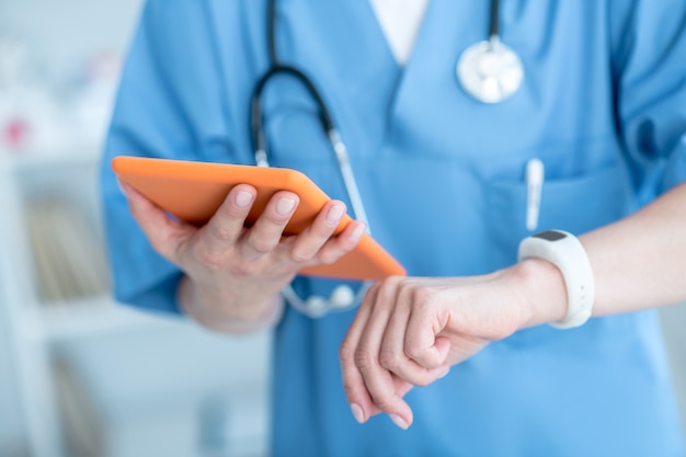 Close up of person looking at smatwatch and holding a tablet