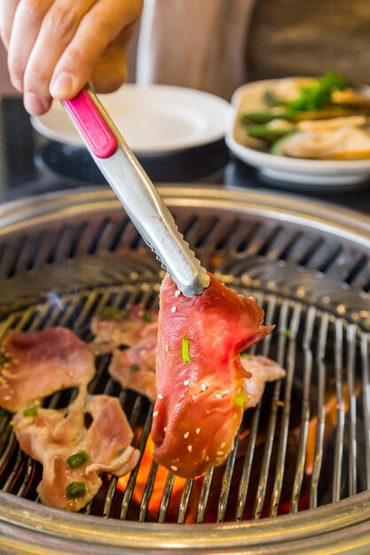 Photo close-up of person preparing food on barbecue grill