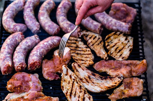 Photo close-up of person preparing meat on barbecue grill