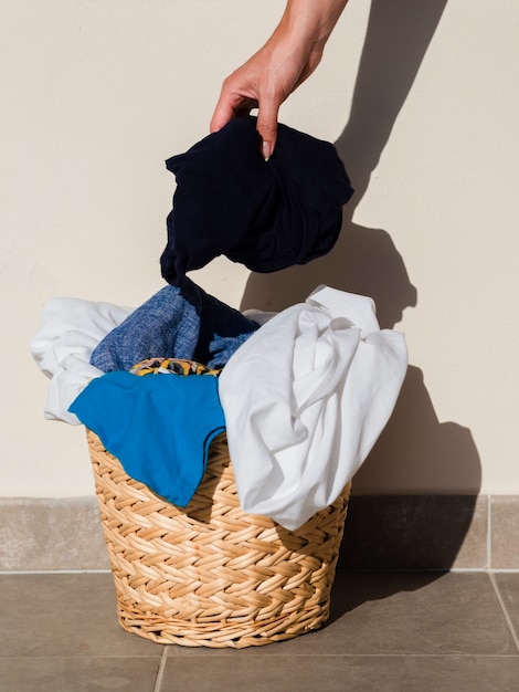 Close up person putting clothes in laundry basket