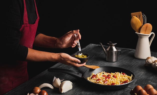 Foto persona del primo piano che mette salsa in pasta