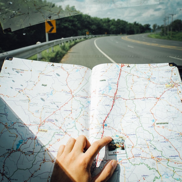 Photo close-up of person reading map in car against sky