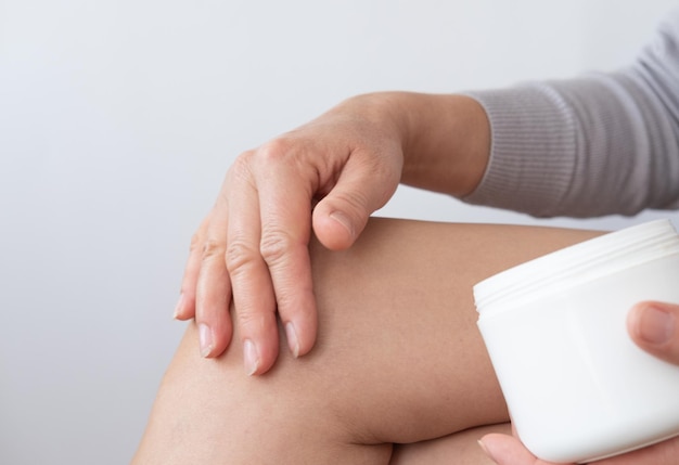 Close up of a person rubbing cream for healing injured knee joint Bruise on the knee Leg pain