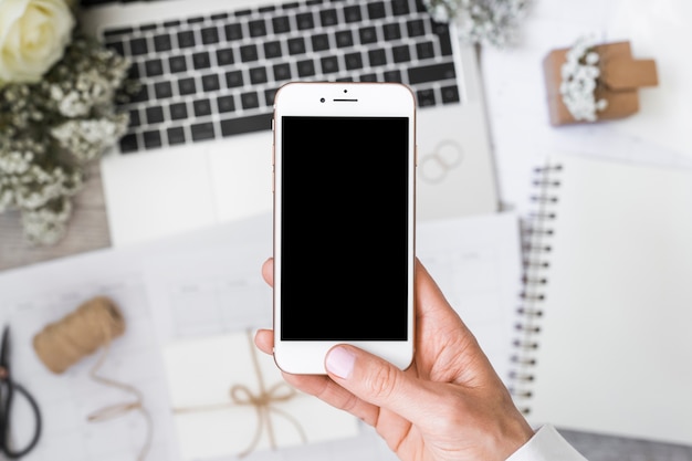 Photo close-up of a person's hand holding smartphone over the desk