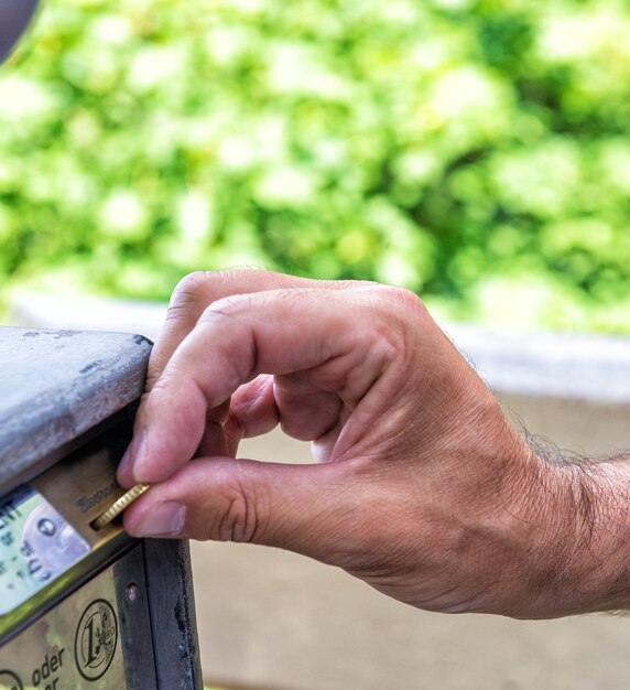 Close-up Of Person's Hand Inserting Ticket Into Parking Machine To Pay For Parking.