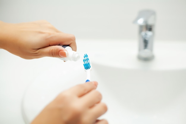 Close up of person using toothpaste and a toothbrush