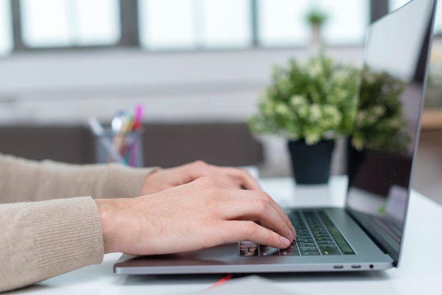 Foto close-up persoon die op laptop vanuit huis werkt