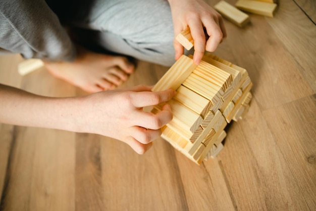 close-up persoon stapelt houten blokken van de ontwerper op de vloer kinderhanden Bordspellen e