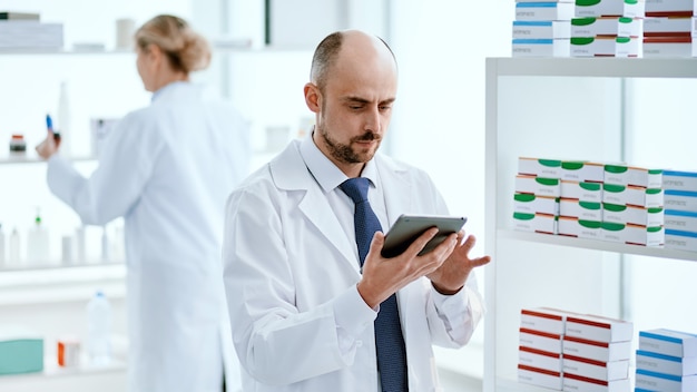 Close-up. pharmacist with a digital tablet standing near a display case with medicines.