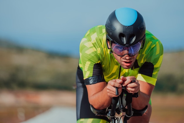 Close up photo of an active triathlete in sportswear and with a protective helmet riding a bicycle. Selective focus.