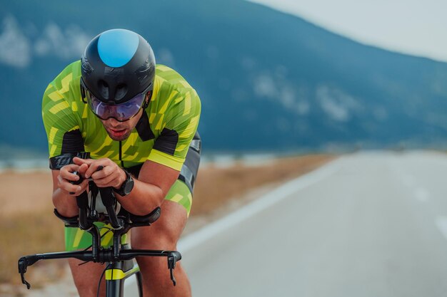 Foto foto ravvicinata di un triatleta attivo in abbigliamento sportivo e con un casco protettivo in bicicletta. messa a fuoco selettiva.